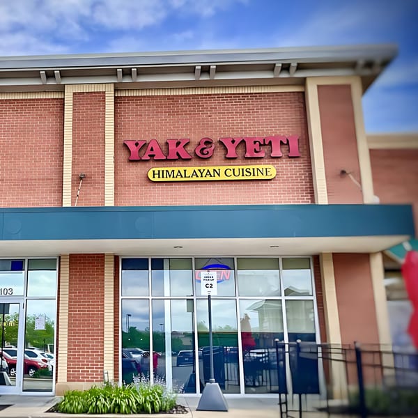 Exterior of Yak & Yeti Himalayan Cuisine restaurant with brick facade, large windows, and signage.