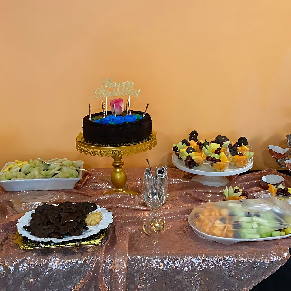 A birthday cake, fruit cups, and cookies on a sequined table at Yak and Yeti Himalayan Cuisine.